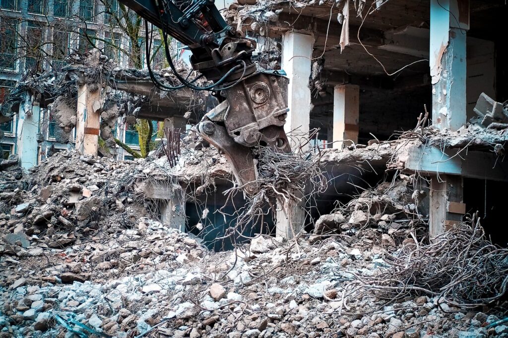 Building being torn down by heavy machinery.
