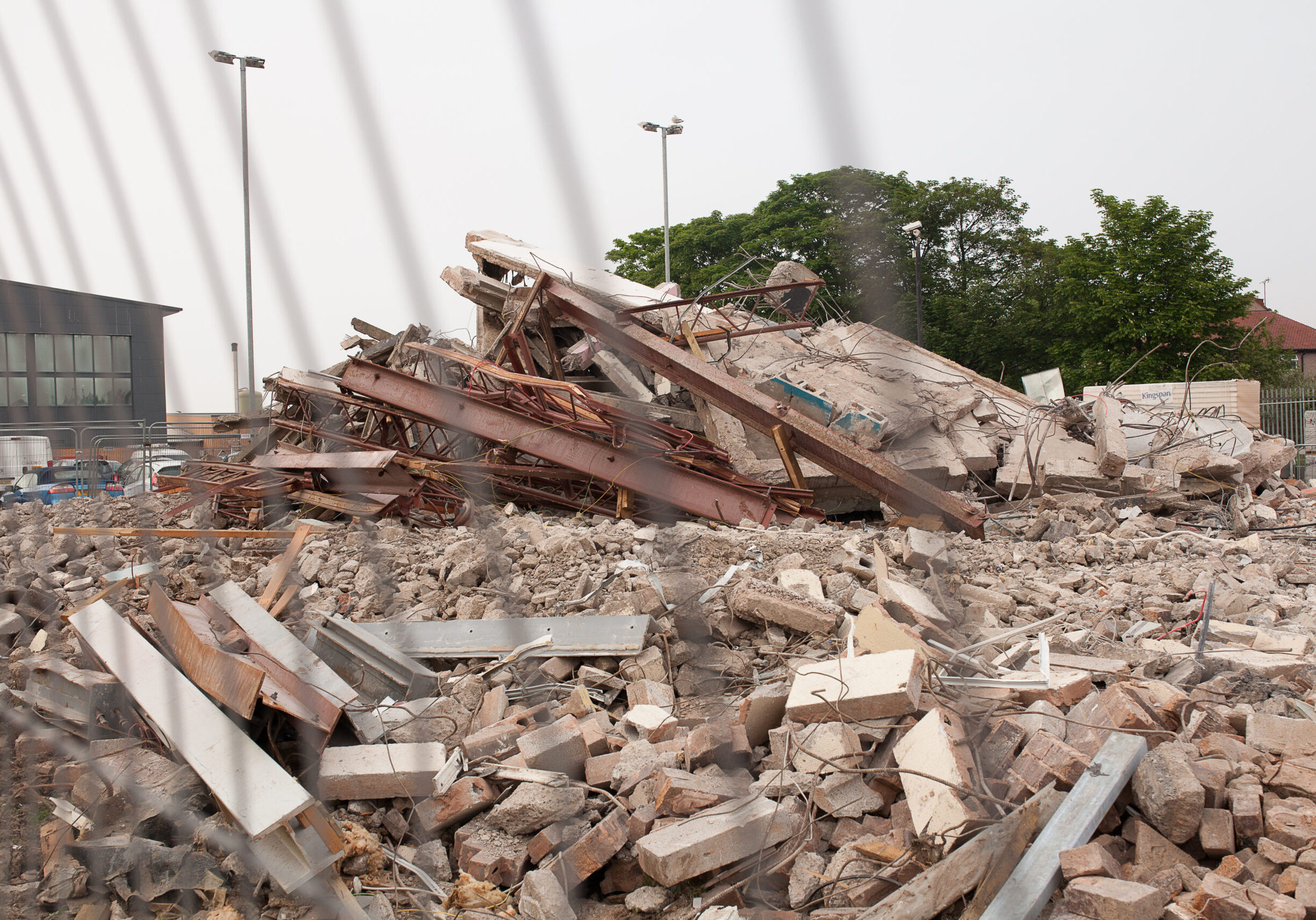 Demolished building rubble. Asbestos exposure risk. Construction debris with beams and concrete fragments.